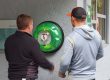 Zwei Personen stehen vor einem Defibrillator an der Wand des Eisplatzes Lindenberg.