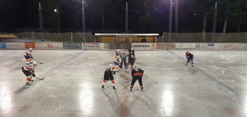 Eishockey-Spielszene bei Nacht auf dem Eisplatz Lindenberg, mehrere Spieler und ein Schiedsrichter im Einsatz.