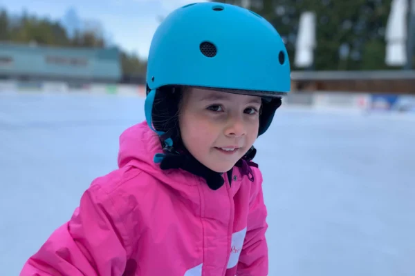 eisplatz_ralf3 Ein Kind mit blauem Helm und pinker Jacke lernt auf der Eisfläche in Lindenberg Eislaufen.