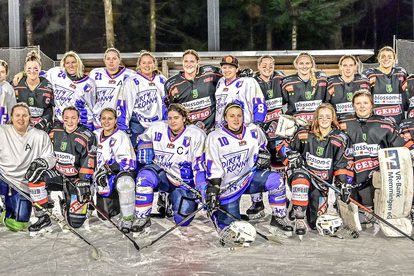 Eine Gruppe von Eishockeyspielern in weißen und schwarzen Trikots posiert für ein Mannschaftsfoto auf einem Eisplatz.