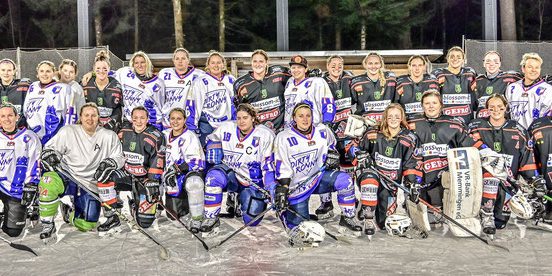 Eine Gruppe von Eishockeyspielern in weißen und schwarzen Trikots posiert für ein Mannschaftsfoto auf einem Eisplatz.
