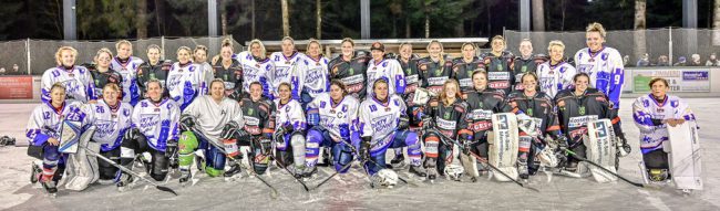 Eine Gruppe von Eishockeyspielern in weißen und schwarzen Trikots posiert für ein Mannschaftsfoto auf einem Eisplatz.