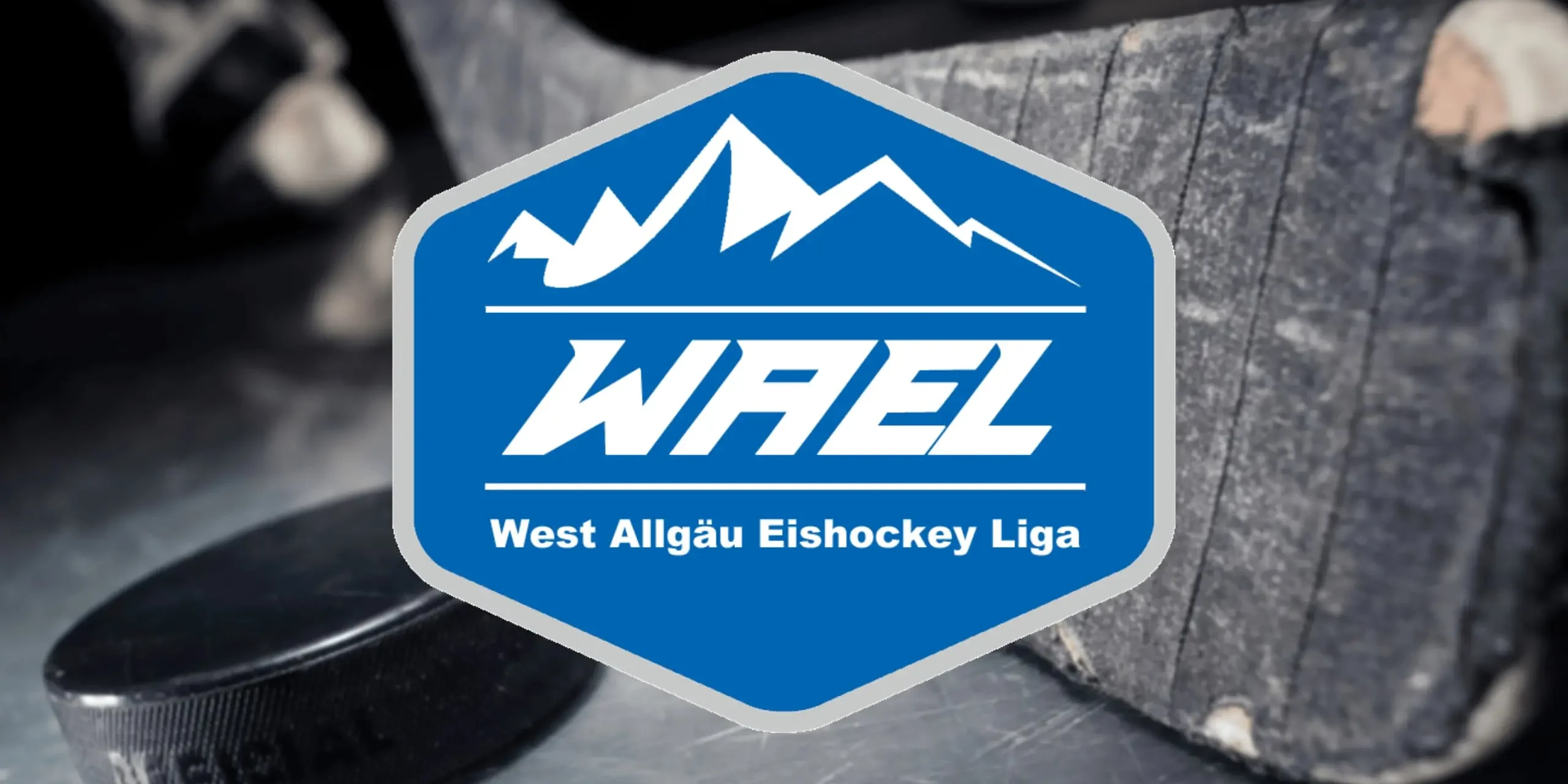 WAEL-Bild-klein Blau-weißes WAEL-Logo der West Allgäu Eishockey Liga vor einem Eishockeyschläger und Puck.