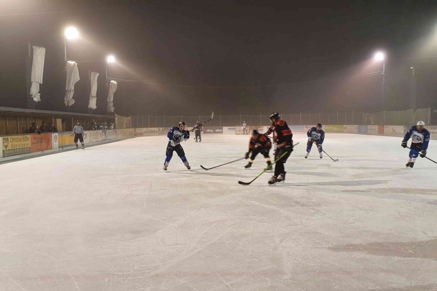 jets Eishockeyspiel bei Nacht auf dem Eisplatz Lindenberg, Spieler in blauen und roten Trikots, beleuchtete Spielfläche.