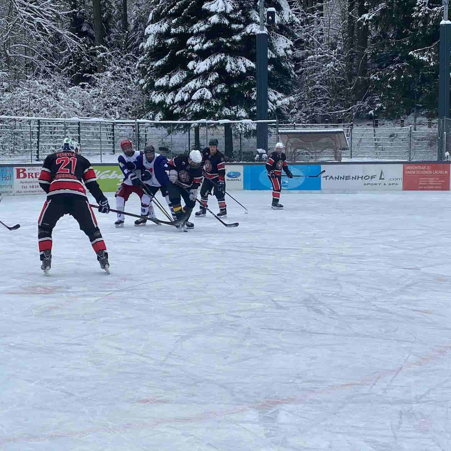 Eishockeyspiel auf einer eisigen Freiluftbahn, Spieler in actionreicher Szene, umgeben von schneebedeckten Bäumen.