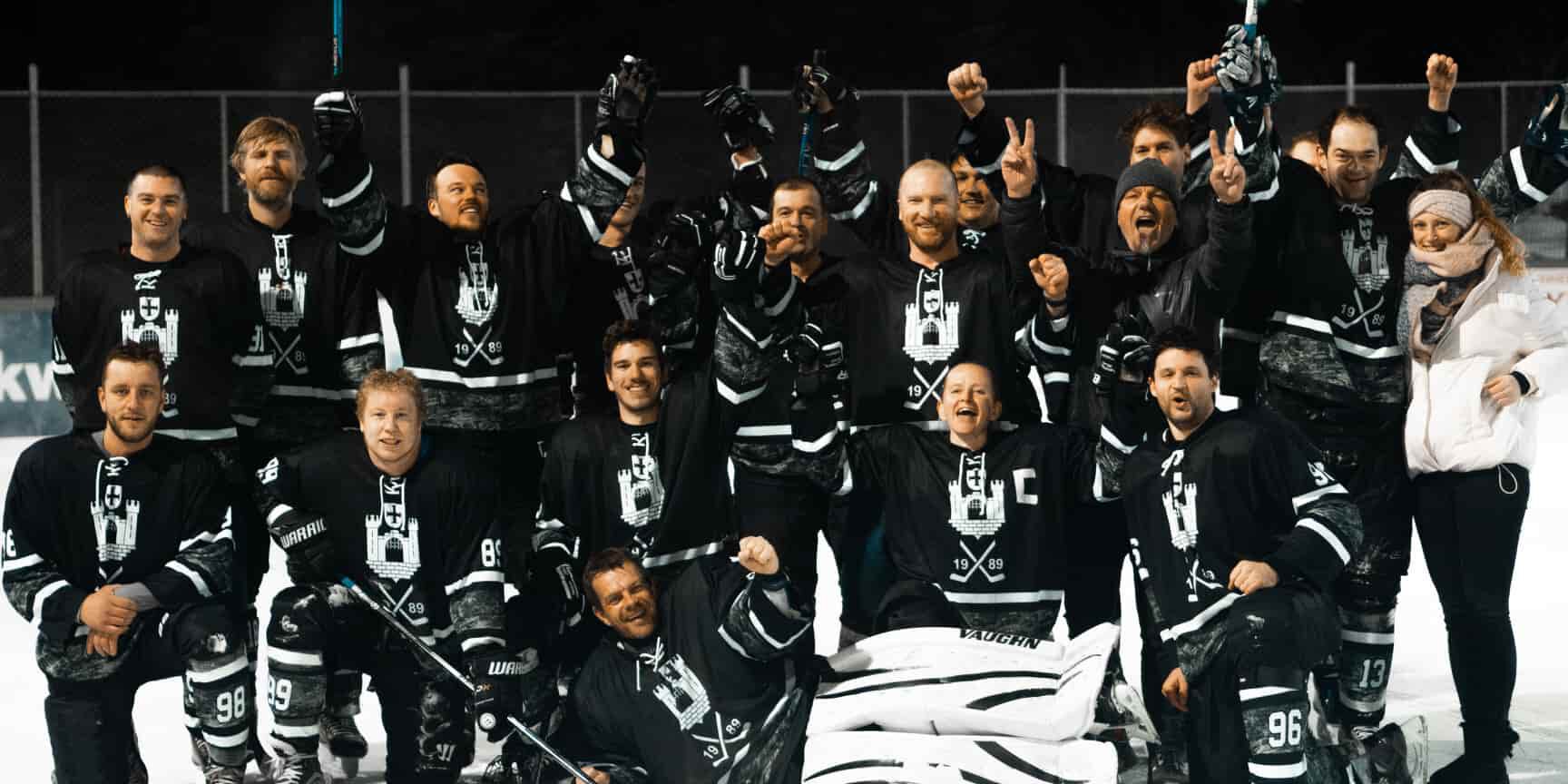 eiskratzer holen den Vorrundensieg 2021/22 Eine Gruppe von Eishockeyspielern in schwarzen Trikots jubelt auf dem Eis des Eisplatzes Lindenberg.