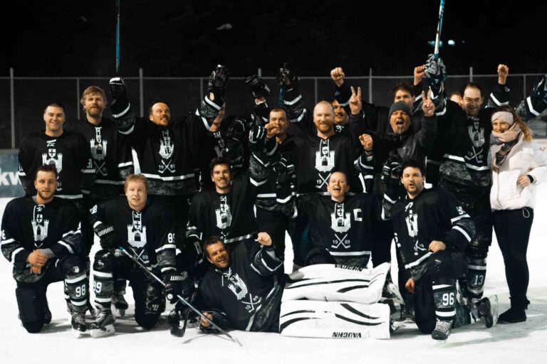 eiskratzer holen den Vorrundensieg 2021/22 Eine Gruppe von Eishockeyspielern in schwarzen Trikots jubelt auf dem Eis des Eisplatzes Lindenberg.