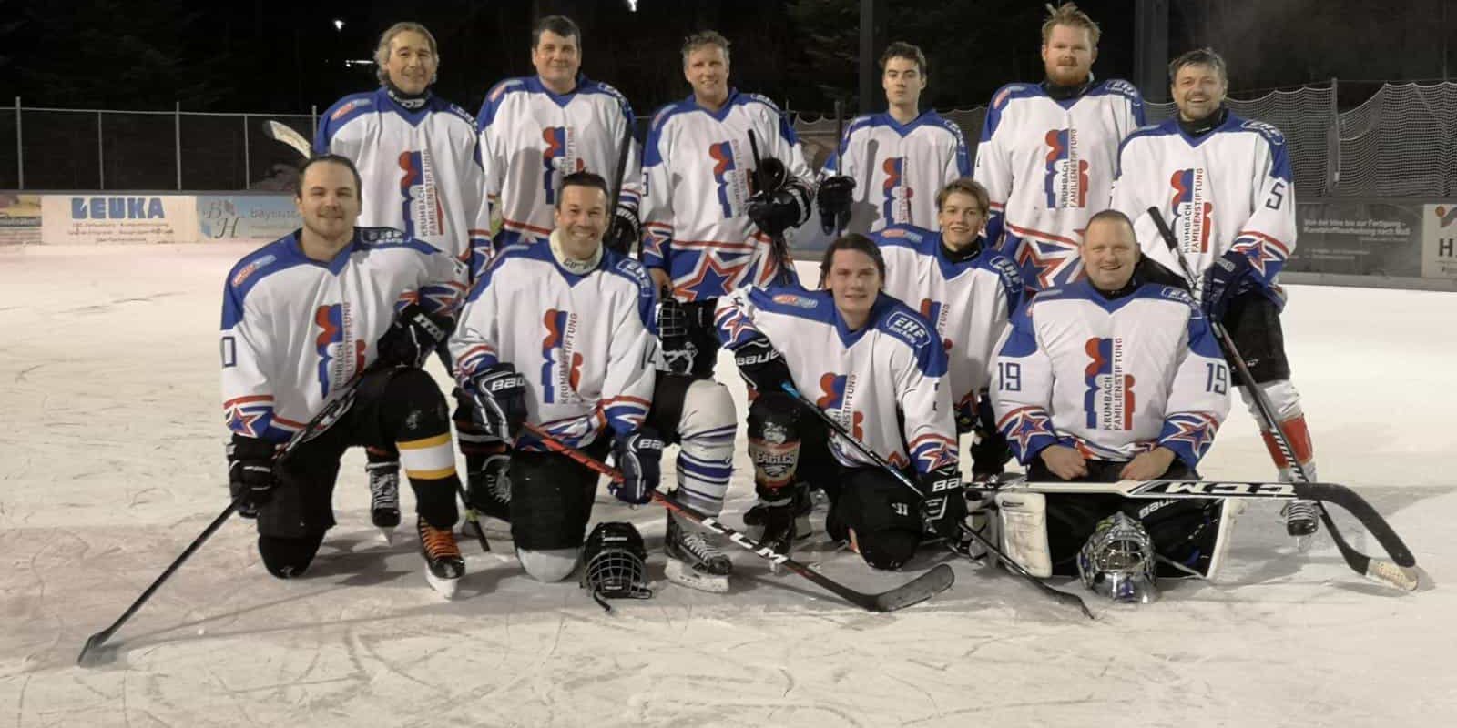 Eishockeymannschaft in weißen Trikots mit blau-roten Details posiert abends auf Eisfläche beim Eisplatz Lindenberg.
