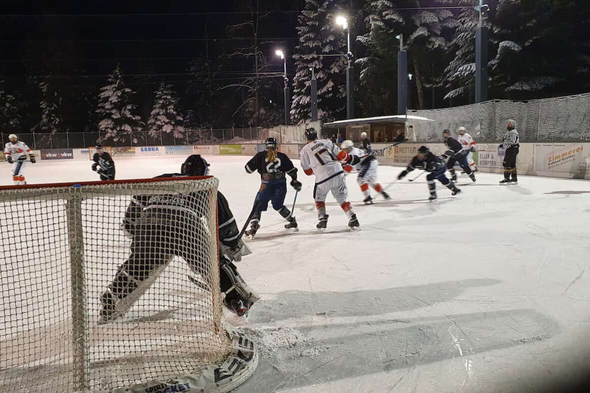 WAEL-Playoffs 2022 Eishockeyspiel bei Nacht auf dem Eisplatz Lindenberg, Spieler in Aktion vor dem Tor, winterliche Kulisse.
