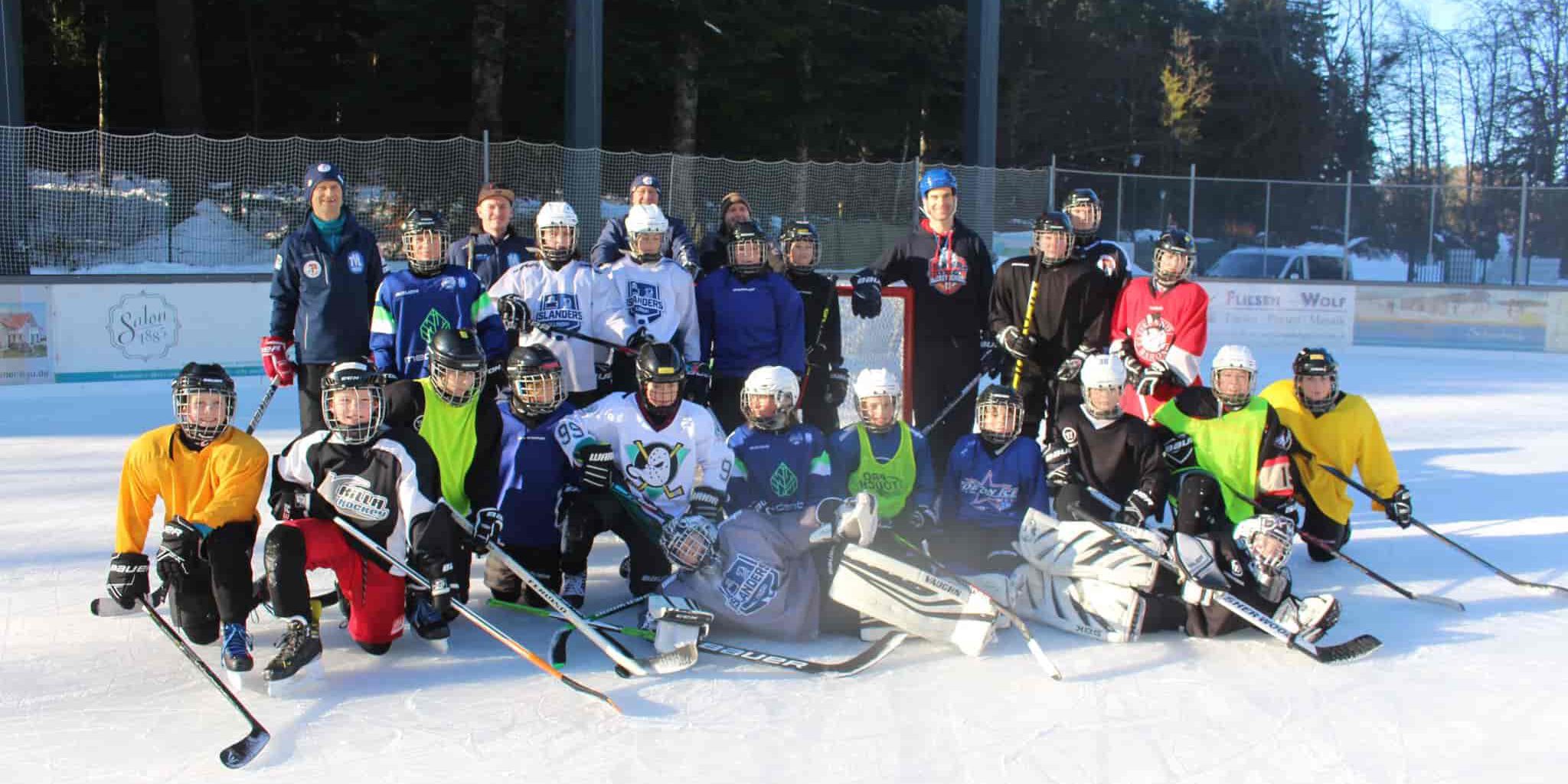 TVL Jugend 21/22 Eine Eishockeymannschaft in verschiedener Ausrüstung posiert lächelnd auf dem Eisplatz Lindenberg für ein Gruppenfoto.