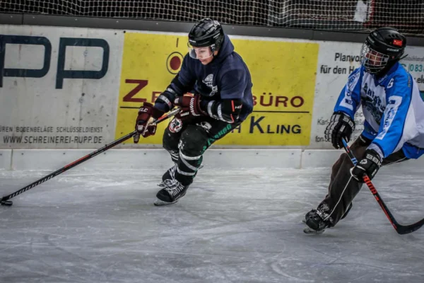 eishockey-hobbyteams Zwei Hobby-Eishockeyspieler in Aktion auf dem Eisplatz Lindenberg, intensiv im Zweikampf um den Puck.