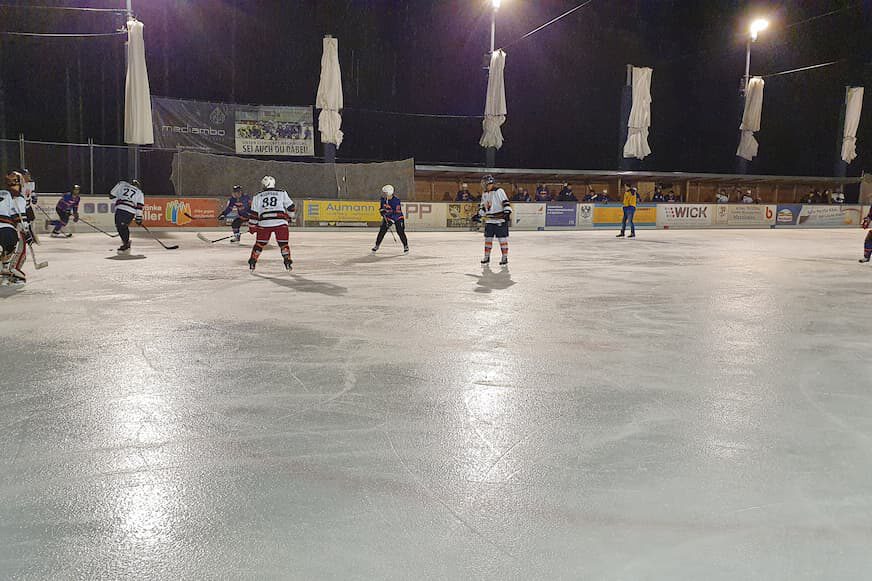 Eishockeyspiel Vorsee Vikings gegen Lindenberg Jets Eishockeyspiel unter Flutlicht auf der Eisfläche in Lindenberg, Spieler in Aktion mit Zuschauern im Hintergrund.