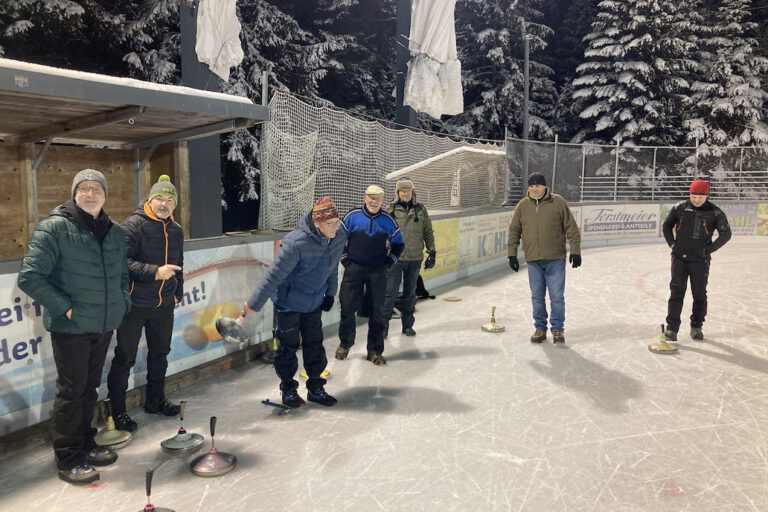 eisstockschiessen Menschen spielen Eisstockschießen auf dem Eisplatz Lindenberg, umgeben von schneebedeckten Bäumen in der Nacht.
