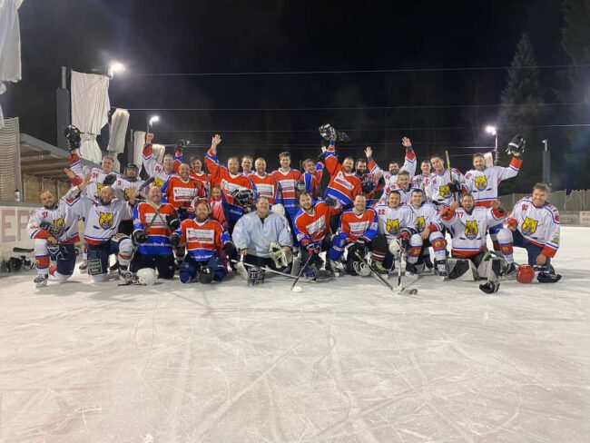 Eishockeymannschaft auf dem Eisplatz Lindenberg feiert gemeinsam in farbigen Trikots bei Nacht unter Flutlicht.