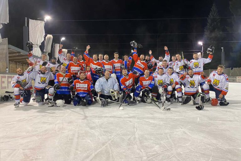 Weiher Wings und Wild Santas aus der WAEL Eishockeymannschaft auf dem Eisplatz Lindenberg feiert gemeinsam in farbigen Trikots bei Nacht unter Flutlicht.