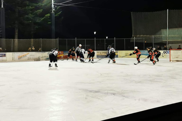 chiefs-eiskratzer-2023 Eishockey-Spiel bei Nacht auf dem Eisplatz Lindenberg, Spieler kämpfen um den Puck, Zuschauer am Spielfeldrand.
