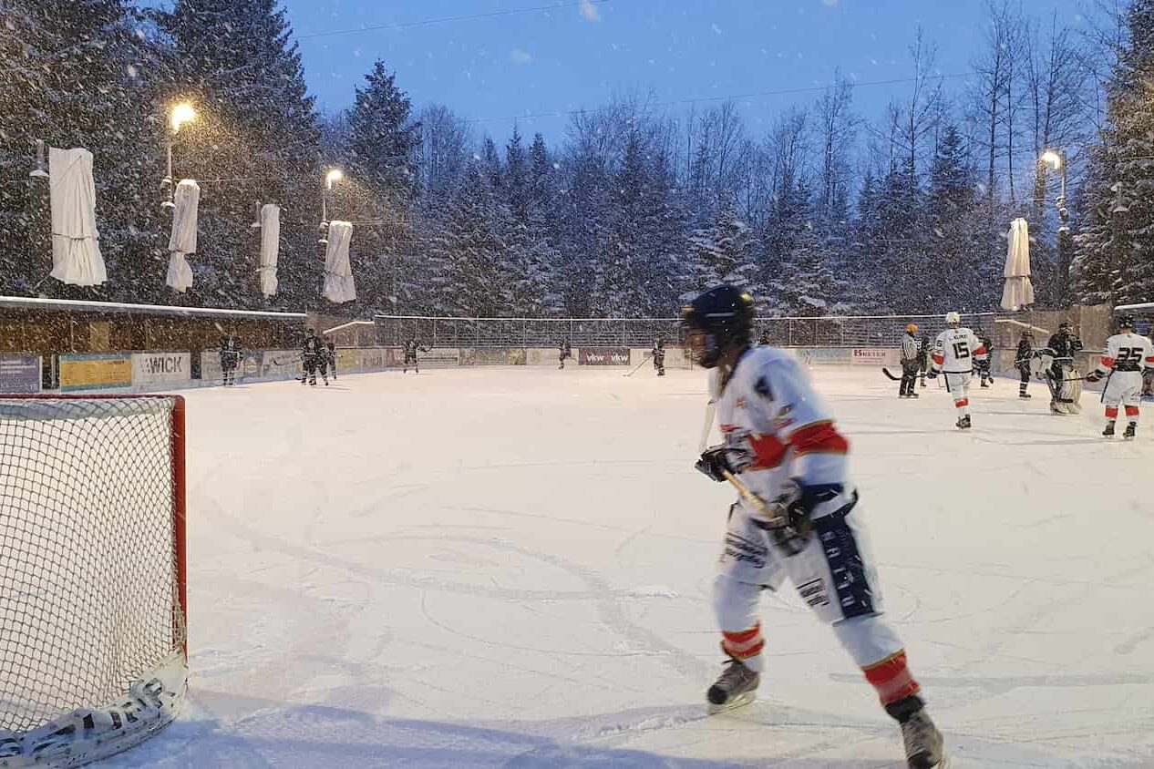 eiskratzer-eagles-21-01-23 Eishockey-Spieler auf dem verschneiten Eisplatz Lindenberg, die Eiskratzer Eagles im Einsatz, umgeben von winterlicher Kulisse.