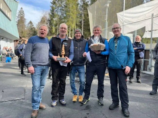 Siegerfoto Turnier 2023 Gruppe Männer hält Trophäen bei Siegerehrung des Turniers 2023 auf dem Eisplatz Lindenberg, lächelnd im Freien.