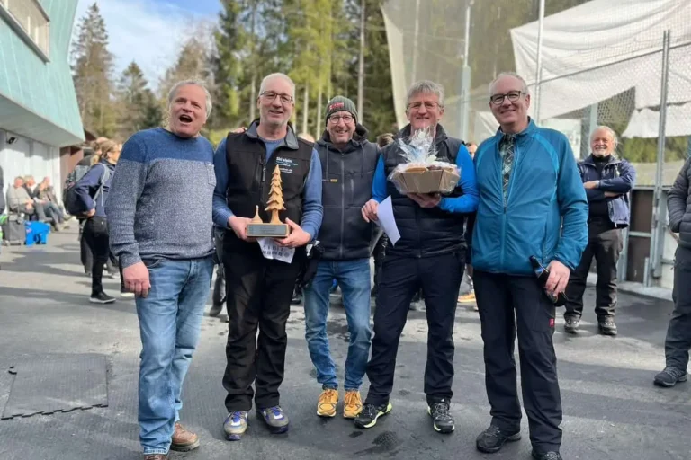 Siegerfoto Turnier 2023 Gruppe Männer hält Trophäen bei Siegerehrung des Turniers 2023 auf dem Eisplatz Lindenberg, lächelnd im Freien.