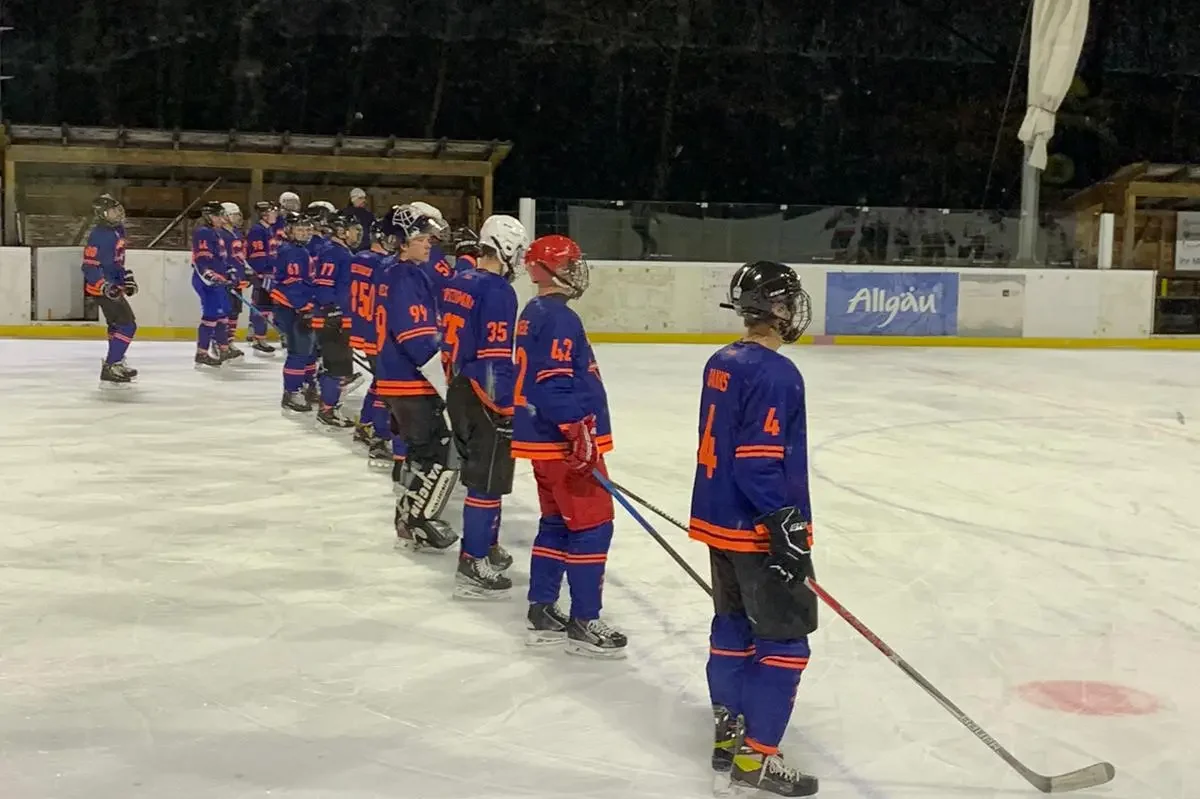 Lindenberg Jets beim Halbfinale in der WAEL 2023 Eishockeyspieler in blauen Trikots stehen in einer Reihe auf dem Eisplatz Lindenberg unter dunklem Himmel.