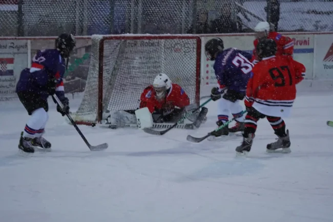 Jugendeishockeyspiel beim TV Lindenberg, Torwart in Rot wehrt Puck ab, Spieler in Rot und Blau kämpfen am Tor.