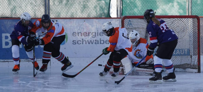 Eishockeyspieler kämpfen um den Puck vor dem Tor auf dem Eisplatz Lindenberg, TVL Bulls in orange und schwarz.