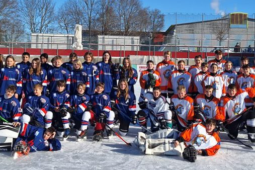 TVL-Jugend-MOD-Januar2024 Jugend-Eishockeymannschaften posieren auf dem Eisplatz Lindenberg in bunter Ausrüstung bei sonnigem Winterwetter.