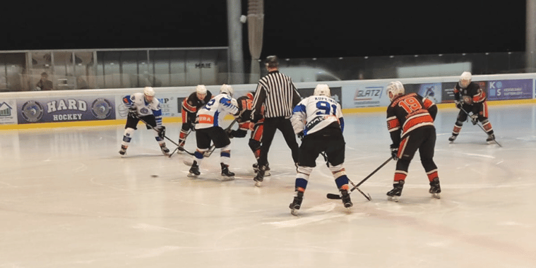 testspiele-chiefs Eishockeyspiel mit sechs Spielern in Aktion; Schiedsrichter bereit für Puck-Einwurf; Hintergrund mit Werbebannern.