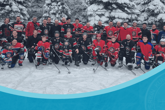 Eine Gruppe von Eishockeyspielern in bunten Teamtrikots posiert lächelnd auf einem verschneiten Eisplatz.