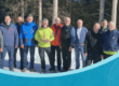 Eine Gruppe von Männern steht im Schnee beim Eisstock-Turnier 2025, einige tragen bunte Jacken.