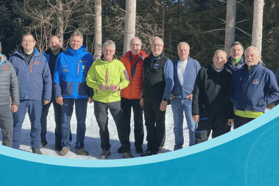 Eine Gruppe von Männern steht im Schnee beim Eisstock-Turnier 2025, einige tragen bunte Jacken.