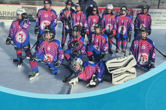 Eine Gruppe Kinder in Eishockey-Ausrüstung posiert auf einer Eisfläche unter einem blauen Banner.