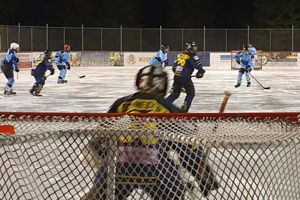 Blick durch das Tornetz auf eine Torhüterin, dahinter Spielerinnen beim Damen-Eishockey auf dem Eisplatz Lindenberg.