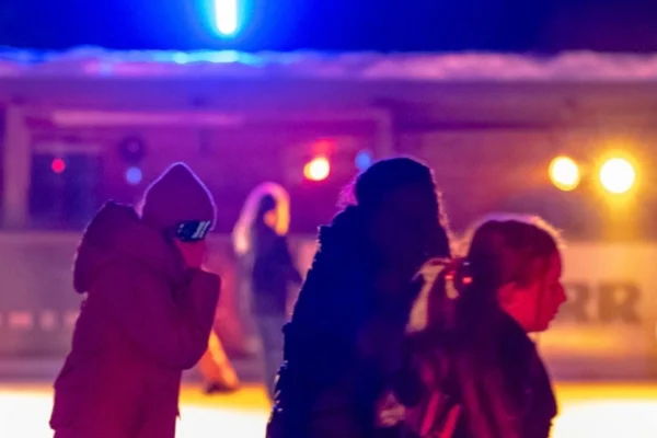 Jugendliche bei der Eisdisco am Eisplatz Lindenberg im bunten Licht von Scheinwerfern.