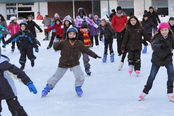 Eine Schulklasse fährt beim Schulsport gemeinsam Schlittschuh auf dem Eisplatz Lindenberg.